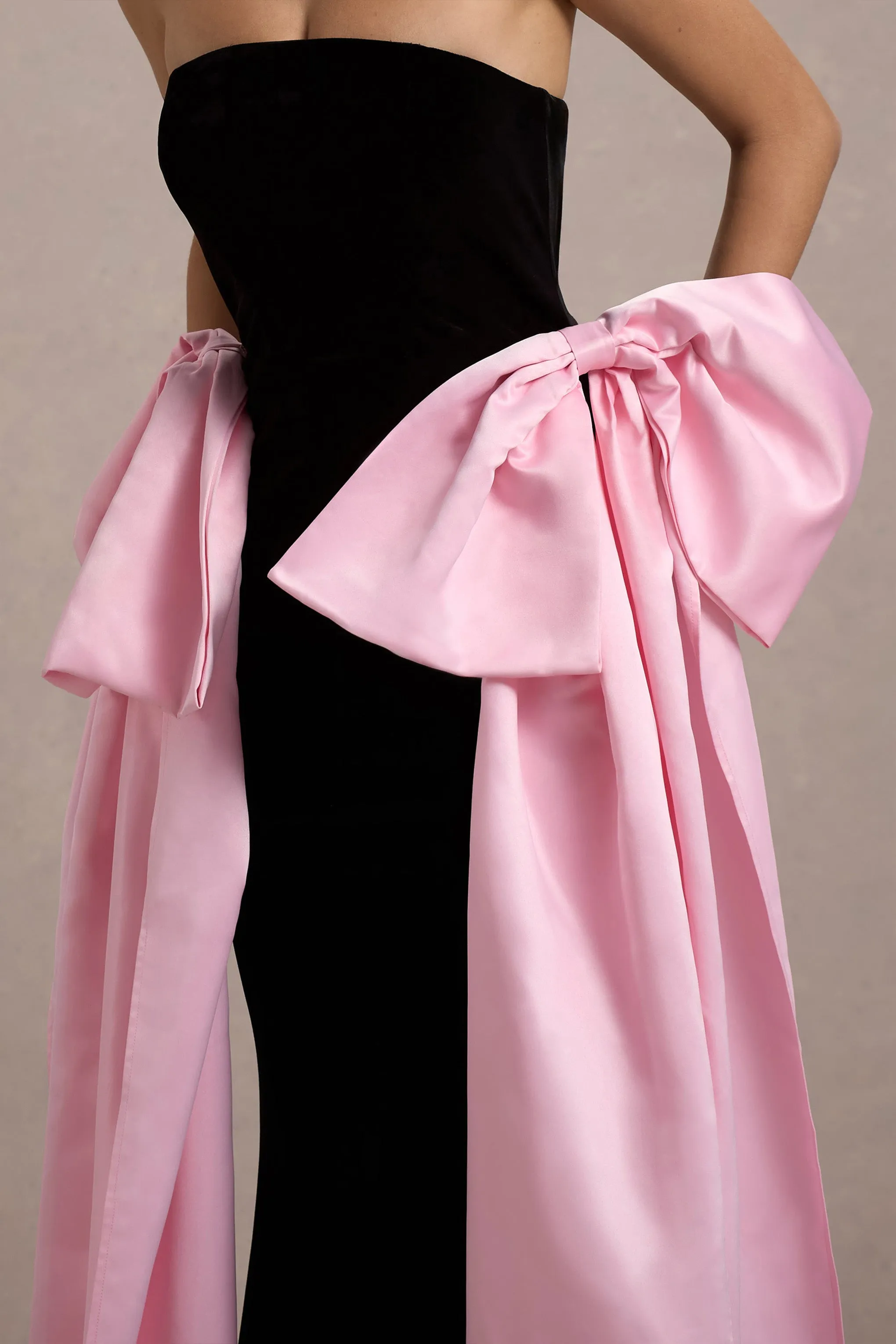 Attention | Robe longue noire sans bretelles avec nuds en satin rose.