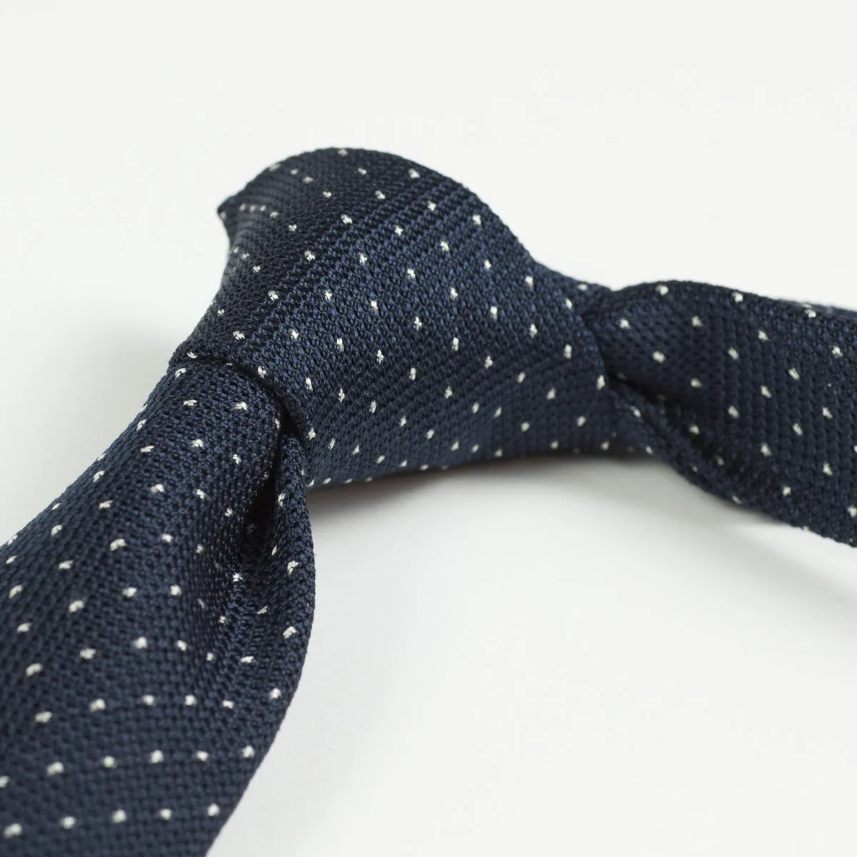 Loosely woven navy silk tie, small white dots